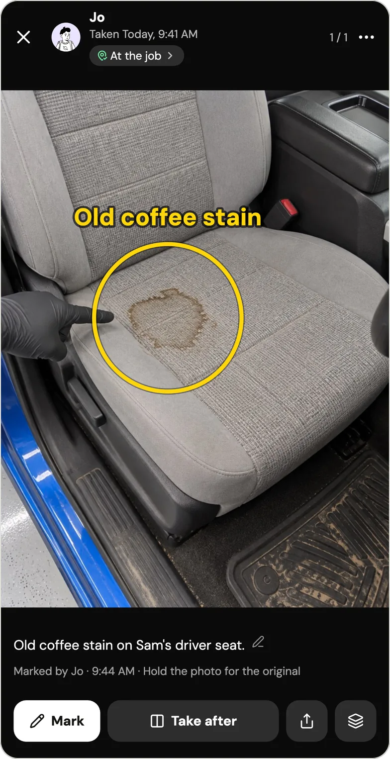 A photo in Handle of a gray cloth driver's seat with a brown stain, a gloved finger pointing at it, circled in yellow with the words Old coffee stain. At the top: Jo, taken today 9:41 AM, At the job. Below: the caption Old coffee stain on Sam's driver seat., then Marked by Jo, 9:44 AM, Hold the photo for the original, and the buttons Mark, Take after and share. The seat photo is a sample from Handle's fictional example crew, not a real job.
